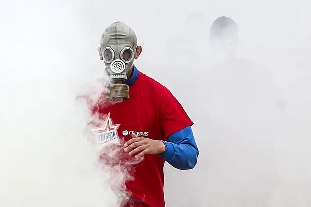A member of the youth sports organisations supported by the military wears a gas mask as he competes in the “Pobeda-2019” obstacle course race at Patriot Park in Moscow Region, Russia on July 12, 2019. (Photo by Valery Sharifulin/TASS)