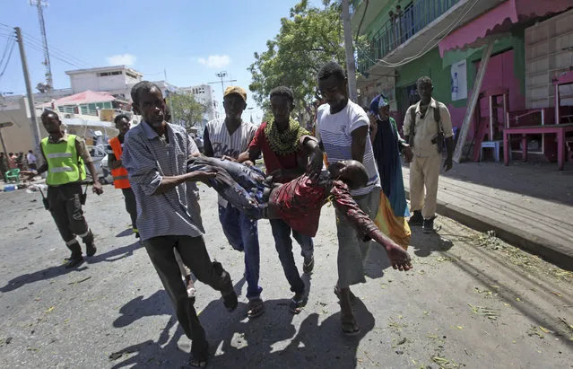 Rescuers carry away a man who was wounded in a car bomb attack in Mogadishu, Somalia Monday, March 13, 2017. (Photo by Farah Abdi Warsameh/AP Photo)