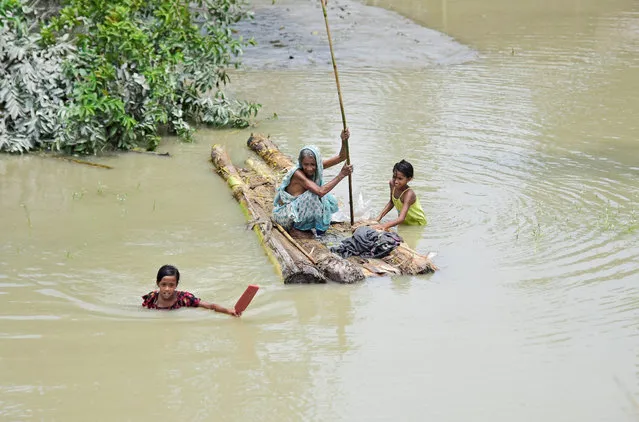 A woman rows a makeshift raft as girls wade through flood waters at the Laharighat village in Morigaon district, in the northeastern state of Assam, India, July 21, 2019. (Photo by Anuwar Hazarika/Reuters)