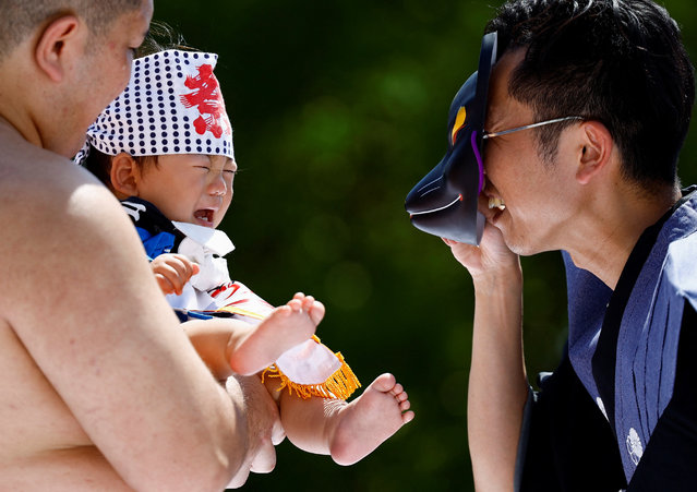 A ring assistant wears a mask to scare a baby held up by an amateur sumo wrestler during “Nakizumo” or a baby-crying sumo contest at Sensoji temple in Tokyo, Japan, on April 28, 2024. (Photo by Issei Kato/Reuters)