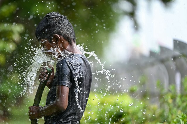 A boy plays with water during a hot summer day in Chennai on May 28, 2024. (Photo by R.Satish Babu/AFP Photo)