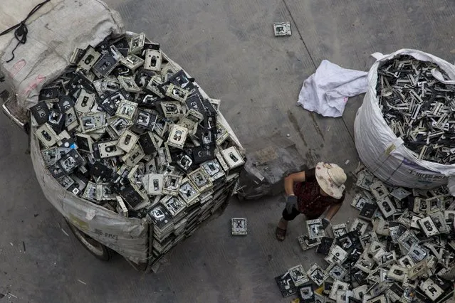 A worker distributes electronic waste at a government managed recycling centre at the township of Guiyu in China's southern Guangdong province June 10, 2015. (Photo by Tyrone Siu/Reuters)