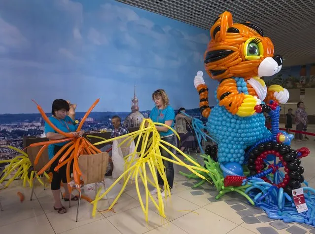 Designers work next to their art work during an international festival of air balloons design in Almaty, Kazakhstan, July 9, 2015. (Photo by Shamil Zhumatov/Reuters)