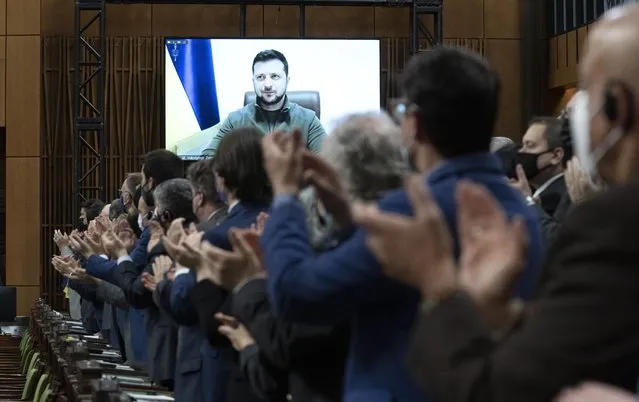 Canadian Members of Parliament and invited guests applaud as Ukrainian President Volodymyr Zelenskyy is shown on a giant video screen before addressing the Canadian parliament, Tuesday, March 15, 2022 in Ottawa. (Photo by Adrian Wyld/The Canadian Press via AP Photo)