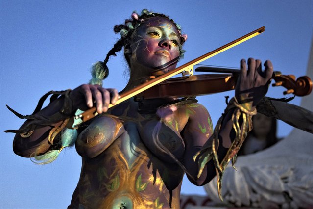 A woman representing the Nuestros Pilares feminist group, plays a violin during a demonstration against gender-based violence marking International Women's Day, in Santiago, Chile, Wednesday, March 8, 2023. (Photo by Esteban Felix/AP Photo)
