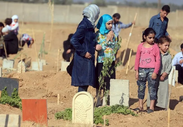 Children pray next to the graves of their relatives at a cemetery, on the first day of the Muslim holiday of Eid al-Fitr, which marks the end of the holy month of Ramadan, in the Douma neighborhood of Damascus, Syria July 17, 2015. (Photo by Bassam Khabieh/Reuters)