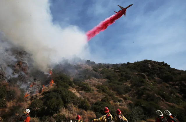 A firefighting aircraft drops the fire retardant Phos-Chek during a wildfire threatening a nearby hillside home in the Pacific Palisades neighborhood on October 21, 2019 in Los Angeles, California. The fire scorched at least 30 acres and prompted mandatory evacuations. (Photo by Mario Tama/Getty Images)