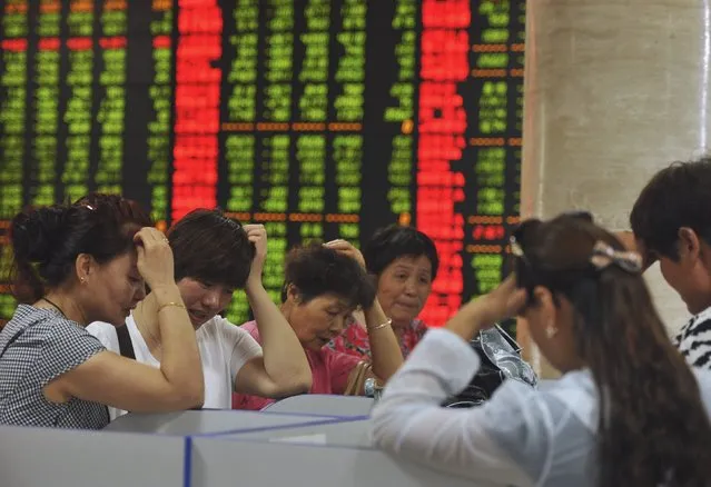 Investors react as they look at computer screens showing stock information at a brokerage house in Fuyang, Anhui province, China, July 28, 2015. Chinese shares fell on Tuesday, as Beijing scrambled once again to prop up a stock market whose wild gyrations have heightened fears about the financial stability of the world's second biggest economy. (Photo by Reuters/Stringer)