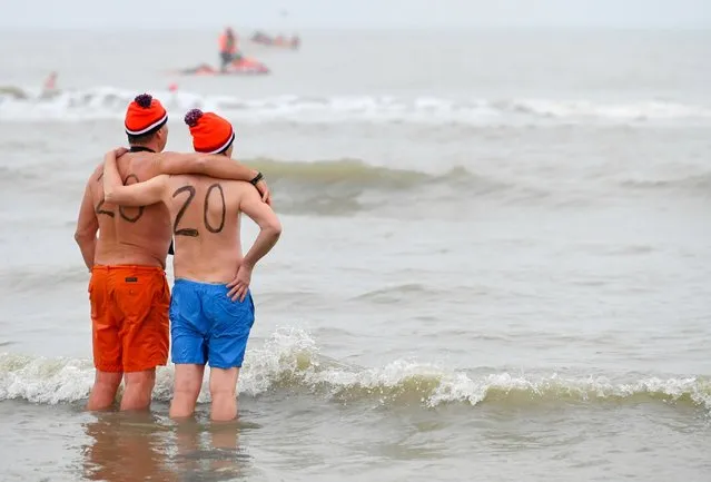 Two men look at the sea while taking part in the annual New Year's dive into the North Sea in Scheveningen, Netherlands on January 1, 2020. (Photo by Piroschka van de Wouw/Reuters)