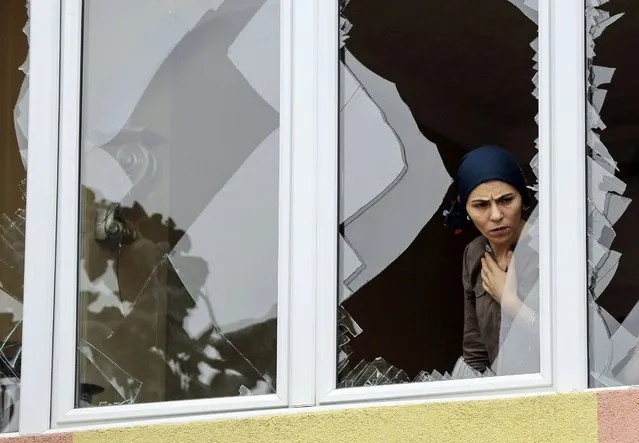 A woman looks on from her shattered window, damaged after an attack on a nearby police station in Istanbul, Turkey, August 10, 2015. (Photo by Huseyin Aldemir/Reuters)