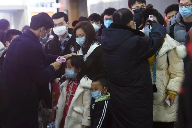 Staff members check body temperatures of the passengers arriving from the train from Wuhan to Hangzhou, at Hangzhou Railway Station ahead of the Chinese Lunar New Year in Zhejiang province, China January 23, 2020. China put millions of people on lockdown on Thursday in two cities at the epicenter of a coronavirus outbreak, as authorities around the world worked to prevent a global pandemic as hundreds of millions of Chinese travel at home and abroad during the Lunar New Year. (Photo by Reuters/China Daily)