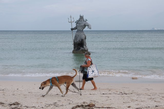 A woman walks past a statue of Poseidon as Hurricane Milton advances, in Progreso, Mexico, on October 7, 2024. (Photo by Lorenzo Hernandez/Reuters)