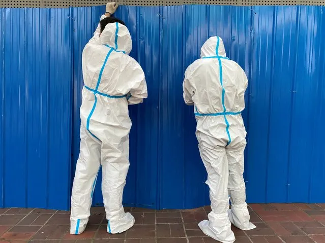 Workers in protective suits set up barriers outside a building, following the coronavirus disease (COVID-19) outbreak, in Shanghai, China on June 9, 2022. (Photo by Andrew Galbraith/Reuters)