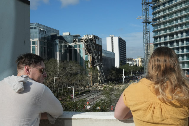 Residents look over a crane that collapsed into a building in downtown St. Petersburg due to Hurricane Milton on October 10, 2024 in Florida. At least four people were confirmed killed as a result of two tornadoes triggered by Hurricane Milton on the east coast of the US state of Florida, local authorities said Thursday. (Photo by Bryan R. Smith/AFP Photo)