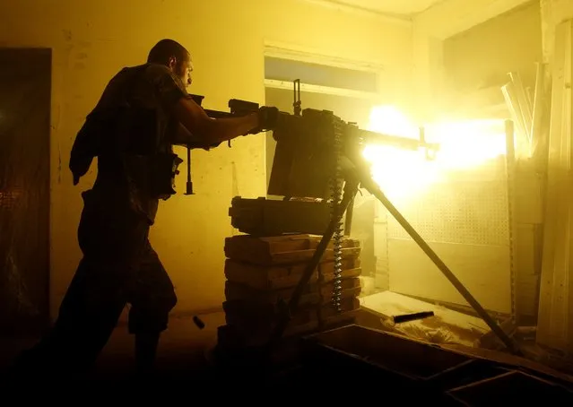 A Ukrainian Forces soldier fires a heavy machine gun during a battle with pro-Russian separatists at Avdeyevka, in Ukraine's Donetsk region on June 25, 2016. (Photo by Anatolii Stepanov/AFP Photo)