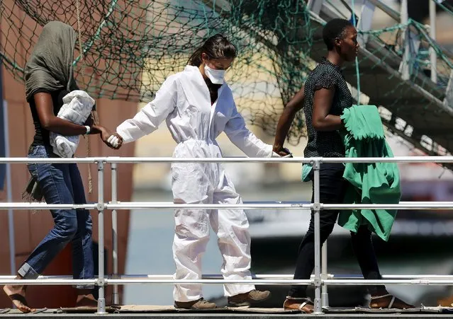 Migrants disembark from the Norwegian ship Siem Pilot as they are helped by a volunteer (C) at the Sicilian harbour of Catania, Italy, August 17, 2015. The Siem Pilot pulled into the port of Catania on Monday carrying 49 migrant bodies believed to have suffocated in the water-logged hold of a fishing boat and some 416 migrants lucky enough to have been rescued at sea. (Photo by Antonio Parrinello/Reuters)
