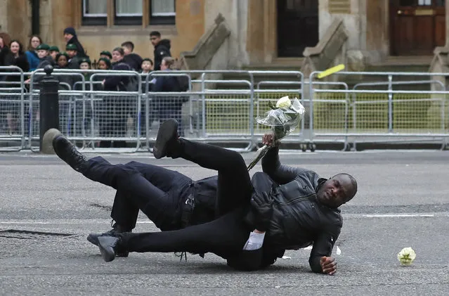 Police officers apprehend a protestor demonstrating against the government of Cameroon outside of the annual Commonwealth Day service at Westminster Abbey in London, Monday, March 9, 2020. The annual service organised by the Royal Commonwealth Society, is the largest annual inter-faith gathering in the United Kingdom. (Photo by Frank Augstein/AP Photo)