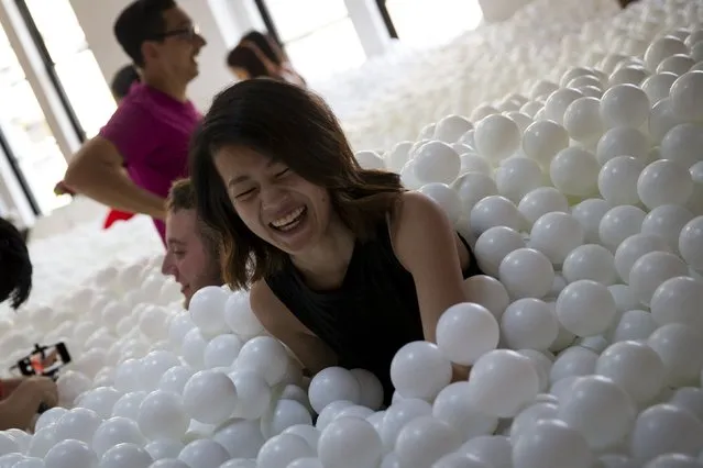 People play in the “JumpIn!” ball pit, an interactive art installation by creative agency Pearlfisher made up of 81,000 white balls, in New York City August 25, 2015. (Photo by Mike Segar/Reuters)