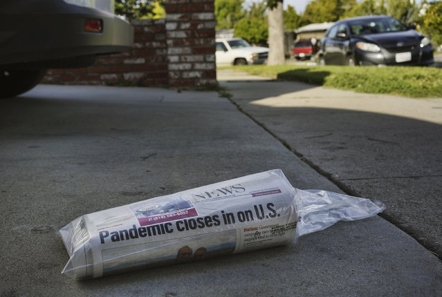 A Sunday paper with a headline that warns of the coronavirus sits in the driveway of a home in the Panorama City section of Los Angeles on Sunday, March 22, 2020. California Gov. Gavin Newsom ordered the state's 40 million residents to stay at home indefinitely. His order restricts non-essential movements to control the spread of the coronavirus that threatens to overwhelm the state's medical system. (Photo by Richard Vogel/AP Photo)