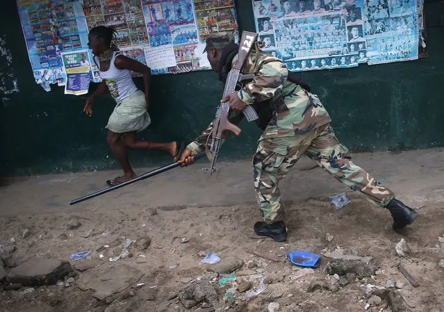A Liberian Army soldier, part of the Ebola Task Force, beats a local resident while enforcing a quarantine on the West Point slum on August 20, 2014 in Monrovia, Liberia. The government ordered the quarantine of West Point, a congested seaside slum of 75,000, on Wednesday, in an effort to stop the spread of the virus in the capital city. (Photo by John Moore/Getty Images)