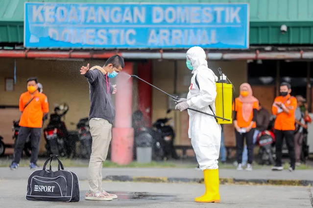 An Indonesian migrant worker (L) who just arrived from Malaysia gets sprayed with disinfectant before entering a quarantine center at Soewondo Air Base in Medan, North Sumatra, Indonesia, 10 April 2020. Countries around the world are taking increased measures to stem the widespread of the SARS-CoV-2 coronavirus which causes the Covid-19 disease. (Photo by Dedi Sinuhaji/EPA/EFE)