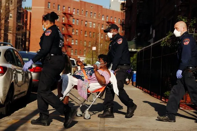 A New York City Fire Department (FDNY) Emergency Medical Technician (EMT) wearing personal protective equipment assist a woman who was having difficulty breathing during ongoing outbreak of the coronavirus disease (COVID19) in New York, April 15, 2020. (Photo by Lucas Jackson/Reuters)