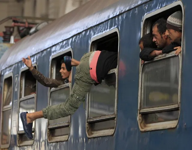 A migrant gets into a train through a window at the Keleti train station in Budapest, Hungary, September 3, 2015 as Hungarian police withdrew from the gates after two days of blocking their entry. (Photo by Bernadett Szabo/Reuters)