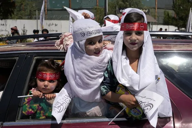 Children hold Taliban flags during a celebration marking the first anniversary of the withdrawal of US-led troops from Afghanistan, in front of the U.S. Embassy in Kabul, Afghanistan, Wednesday, August 31, 2022. (Photo by Ebrahim Noroozi/AP Photo)