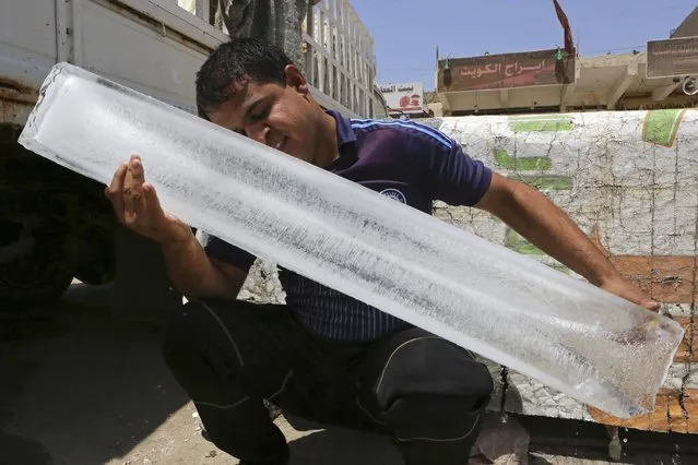 A man cools his face after buying a block of ice for the equivalent of $4 in Basra, 340 miles (550 kilometers) southeast of Baghdad, Iraq, Monday, August 1, 2016. The temperature in Basra reached 49 degrees Celsius (120 Fahrenheit) on Monday. (Photo by Nabil al-Jurani/AP Photo)