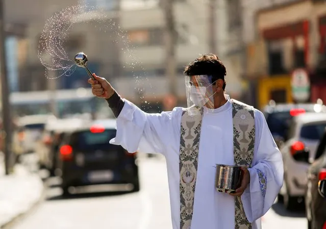 Catholic priest Reginaldo Manzotti sprinkles holy water on drivers at the blessing drive-thru system during the Mothers Day, as the spread of the coronavirus disease (COVID-19) continues in Curitiba, Brazil, May 10, 2020. (Photo by Rodolfo Buhrer/Reuters)