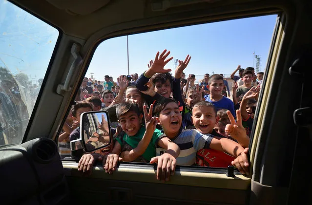 Iraqi boys gather on the road as they welcome Iraqi security forces members, who continue to advance in military vehicles in Kirkuk, Iraq October 16, 2017. (Photo by Reuters/Stringer)