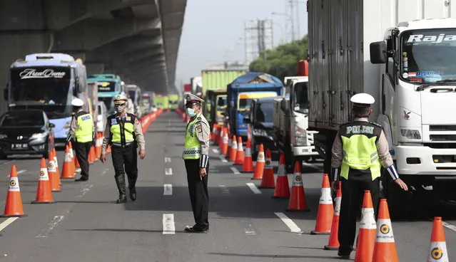 Indonesian police guard at a checkpoint during the imposition of large-scale restriction to curb the spread of the new coronavirus outbreak on a toll road in Cikarang, West Java, Indonesia, Friday, April 24, 2020. Indonesia is suspending passenger flights and rail service as it restricts people in the world's most populous Muslim nation from traveling to their hometowns during the Islamic holy month of Ramadan because of the coronavirus outbreak. (Photo by Achmad Ibrahim/AP Photo)