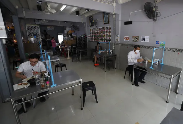 Customers eat lunch behind plastic shields to to help curb the spread of the coronavirus in Bangkok, Thailand, Tuesday, May 5, 2020. Easing of restrictions in Thailand's capital Bangkok that were imposed weeks ago to combat the spread of the coronavirus, with re-opening restaurants as long as social distancing guidelines are observed. (Photo by Sakchai Lalit/AP Photo)
