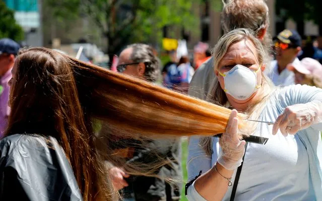 Randi Bates cuts hair during the Michigan Conservative Coalition organized “Operation Haircut” outside the Michigan State Capitol in Lansing, Michigan on May 20, 2020. The group is protesting Michigan Governor Gretchen Whitmer's mandatory closure to curtail the coronavirus pandemic. (Photo by Jeff Kowalsky/AFP Photo)