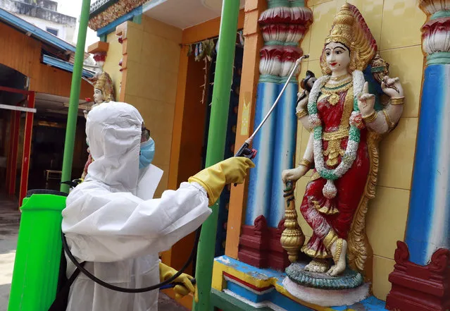 A member of the military wearing full protective gear sprays disinfectant at a Hindu temple to help curb the spread of the new coronavirus in Naypyitaw, Myanmar, Wednesday, April 1, 2020. (Photo by Aung Shine Oo/AP Photo)