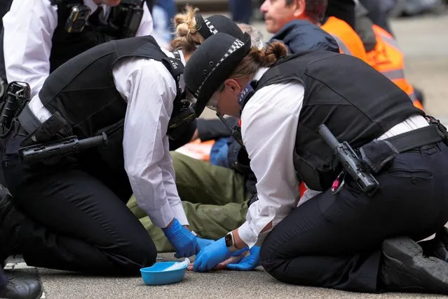Police officers unglue Just Stop Oil activists who had glued themselves to the ground during a protest, in London, Britain on October 5, 2022. (Photo by Maja Smiejkowska/Reuters)