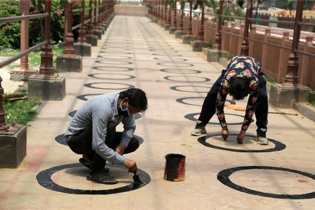 Workers draw circles to maintain social distance for the devotees on premises of the historical temple of the Goddess Kali, during the ongoing lockdown amid coronavirus covid-19 alert in Jammu, India, 04 June 2020. According to media reports, the Indian government has decided to provide some relaxation in the ongoing lockdown which will continue through 30 June 2020. Restrictions will be eased in a phased manner with places of worship, hospitality services and shopping malls scheduled to be opened in the initial phase. The areas termed as “containment zones” will be identified by authorities and will remain under complete lockdown. (Photo by Jaipal Singh/EPA/EFE)