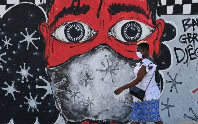 A woman walks past graffiti on a wall depicting hygiene measures to curb the spread of the COVID-19 coronavirus in Abidjan on May 15, 2020. Ivory Coast will on May 15, 2020 lift an almost two-month curfew in its main city Abidjan but nightclubs, cinemas and bars will remain closed to fight the COVID-19 coronavirus epidemic. (Photo by Issouf Sanogo/AFP Photo)