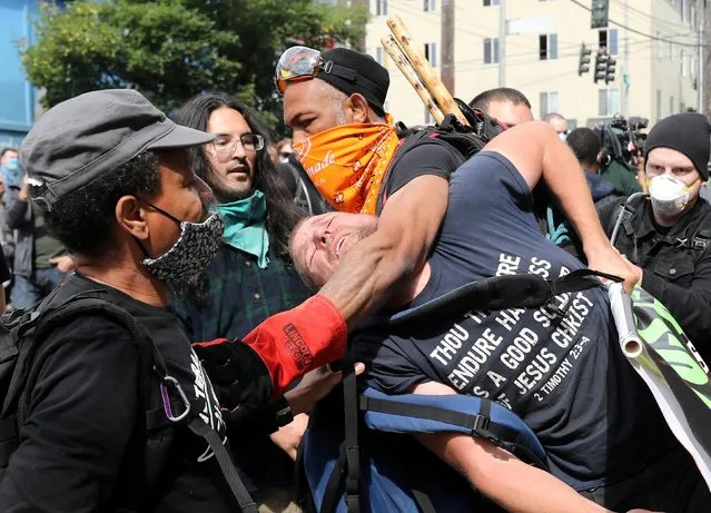 Protesters remove a man from the protest because he was bothering other protesters at the self-proclaimed Capitol Hill Autonomous Zone (CHAZ) during a protest against racial inequality and call for defunding of Seattle police, in Seattle, Washington, U.S. June 13, 2020. (Photo by Goran Tomasevic/Reuters)