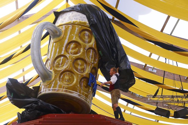 Andreas Steinfatt of the Paulaner brewery unveils a huge beer mug figure in preparation for the Oktoberfest in Munich, Germany September 16, 2015. Millions of beer drinkers from around the world are expected to attend the 182nd Oktoberfest beer festival, which opens on September 19, 2015. (Photo by Michael Dalder/Reuters)