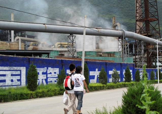 Residents walk past a zinc smelter belonging to the Dongling Group, in Fengxian county, Shaanxi province, August 22, 2009. (Photo by Lucy Hornby/Reuters)