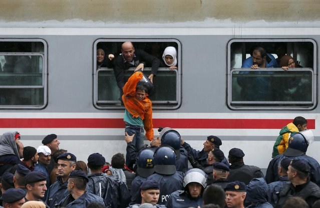 Migrants pull a boy through a train window at the station in Tovarnik, Croatia, September 20, 2015. (Photo by Antonio Bronic/Reuters)