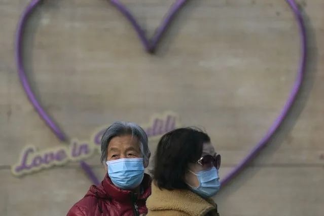 Women wearing face masks stand near a heart-shaped decoration in Beijing, Tuesday, November 22, 2022. (Photo by Andy Wong/AP Photo)