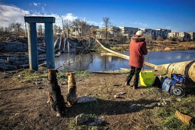 A local resident stands next to a destroyed bridge in Bakhmut, Donetsk region, on November 29, 2022, amid the Russian invasion of Ukraine. Once known for its vineyards and cavernous salt mines, Bakhmut has now been dubbed “the meat grinder” due to the brutal trench warfare, artillery duels and frontal assaults that have defined the brutal fight for the city for over six months. (Photo by Yevhen Titov/AFP Photo)
