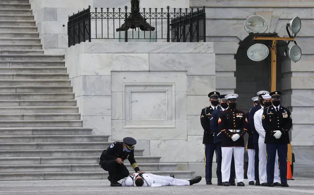 A member of a U.S. military honor guard is checked on after collapsing in the heat of the day as a hearse carrying the casket of civil rights pioneer and longtime U.S. Rep. John Lewis (D-GA), who died July 17, arrives at the U.S. Capitol prior to Lewis lying in state inside the Rotunda in Washington, U.S., July 27, 2020. (Photo by Leah Millis/Reuters/Pool)