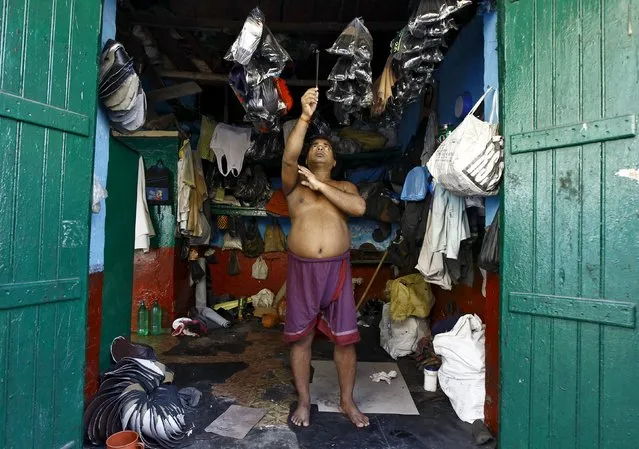 A shopkeeper holds burning incense as he prays inside his shop before the start of his business day in Kolkata, India, September 28, 2015. (Photo by Rupak De Chowdhuri/Reuters)