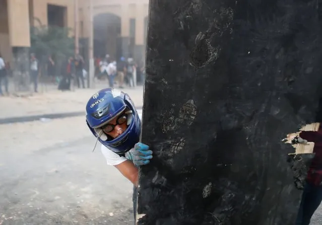 A demonstrator looks at police as he hides behind an improvised shield during a protest following Tuesday's blast in Beirut's port area, in Beirut, Lebanon, August 9, 2020. (Photo by Goran Tomasevic/Reuters)