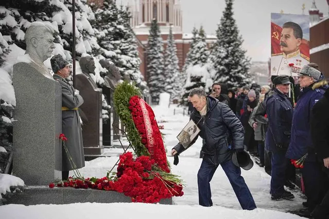 A Communist party supporter wearing a portrait of Soviet leader Josef Stalin lays flowers at his grave marking the 143rd anniversary of his birth near the Kremlin Wall in Red Square in Moscow, Russia, Wednesday, December 21, 2022. (Photo by Alexander Zemlianichenko/AP Photo)