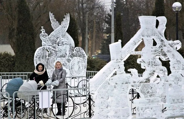 Women walk with strollers along an ice sculptures alley on display as part of New Year and Christmas decorations in Podolsk, outside Moscow, Russia, 27 December 2022. Russians are preparing to celebrate New Year's Eve on 31 December and Christmas, which is observed on 07 January, according to the Russian Orthodox Julian calendar, 13 days after Christmas on 25 December, on the Gregorian calendar. (Photo by Maxim Shipenkov/EPA/EFE)
