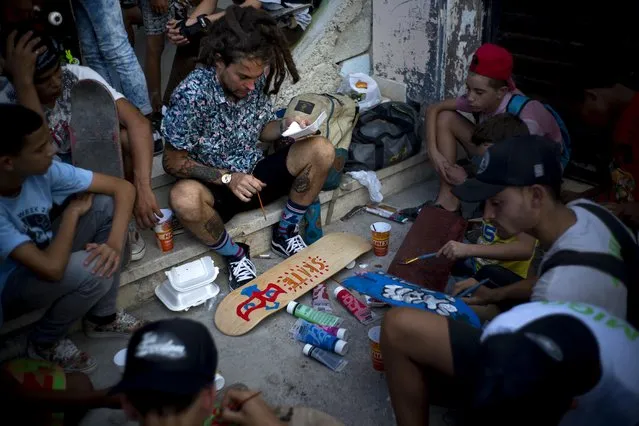 In this January 11, 2018 photo, Canadian skater Chris Dyer paints a skateboard inside an abandoned gym that was converted into a recreational space for skateboarders, the day of its inauguration inside the Educational complex Ciudad Libertad, a former military barracks that the late Fidel Castro turned into a school complex after the revolution in Havana, Cuba. For the skate park's grand opening, musicians performed short free concerts while young skaters got 60 newly donated skateboards and painted old ones. (Photo by Ramon Espinosa/AP Photo)